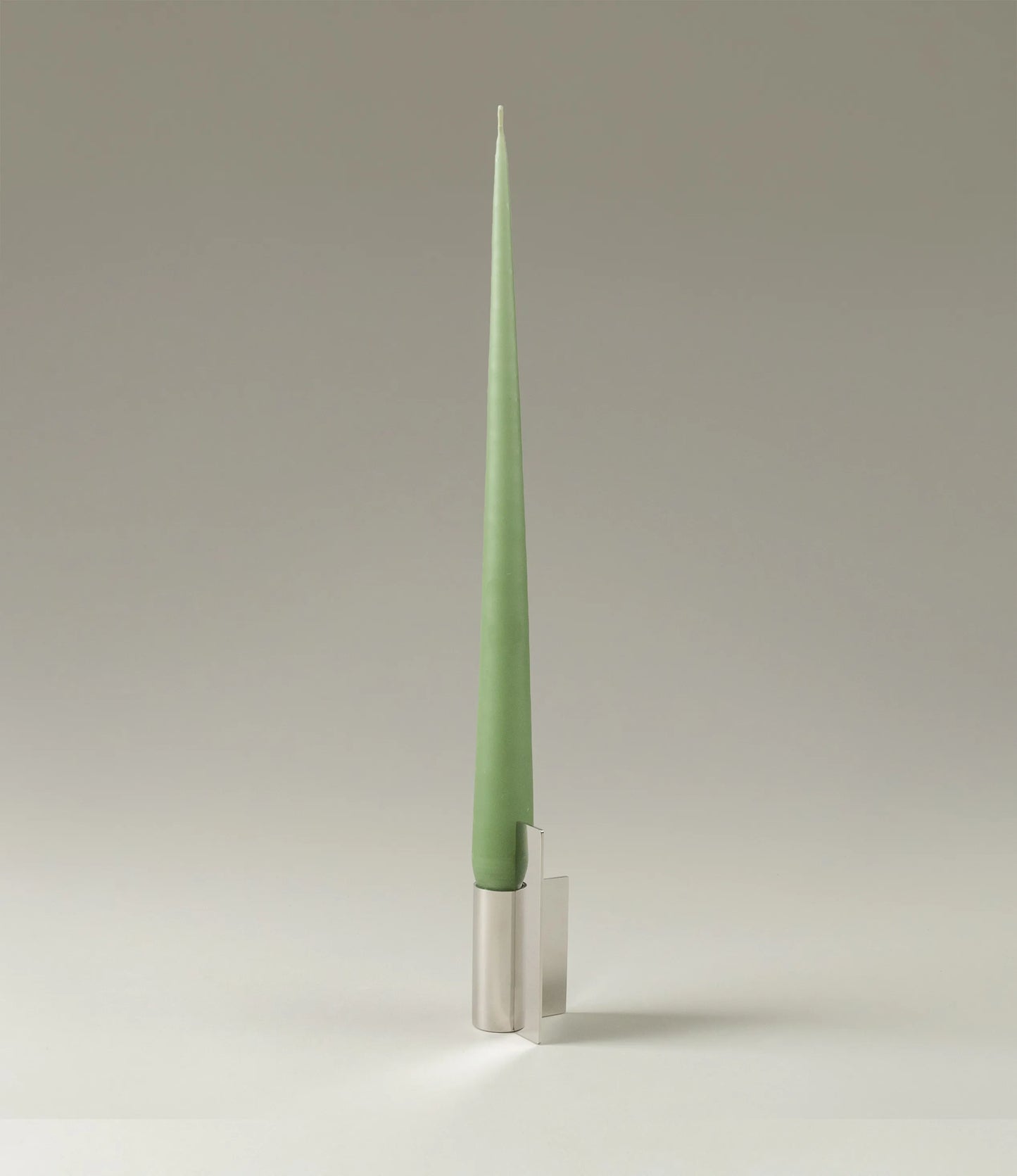 Ester&Erik Taper Candle coming in an eucaliptus shade. The product is showcased in a stainless steel Icon Candleholder from Stences.