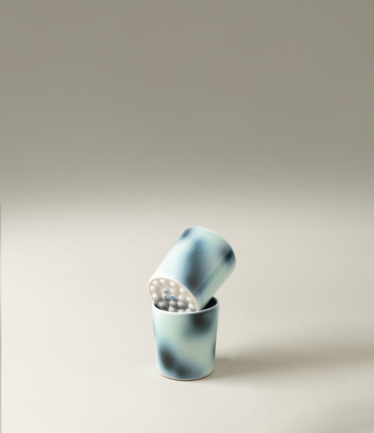 Bulle Cup from Frizbee Ceramics has a unique gradient painted pattern. The product has cold colors like green, dark and light blue. The bottom of the cup looks like it's made of small bubbles.