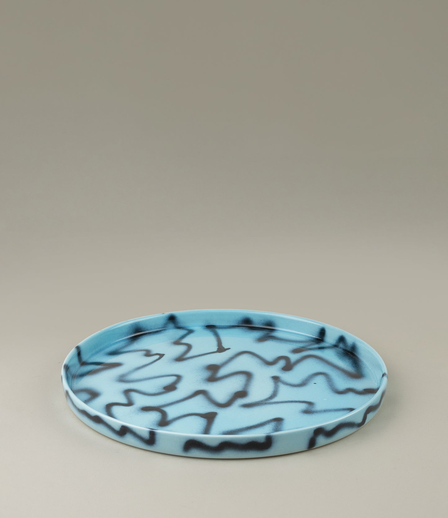 Blue Pizza Tray from Frizbee Ceramics. The tray is coming in the soothing light blue color matched with the contrasting black zig-zag pattern.