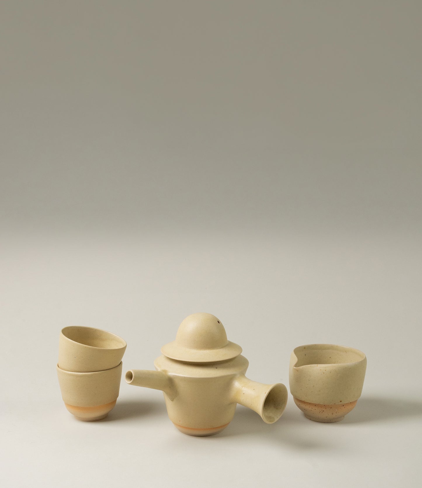 A set from Omni Ceramics for the special tea rituals. The unique shaped teapot, the 2 cups and the pourer are the perfect match. The subtle beige color with the soft radient orange glow on the bottom are a nice touch to any kitchen or dining room.