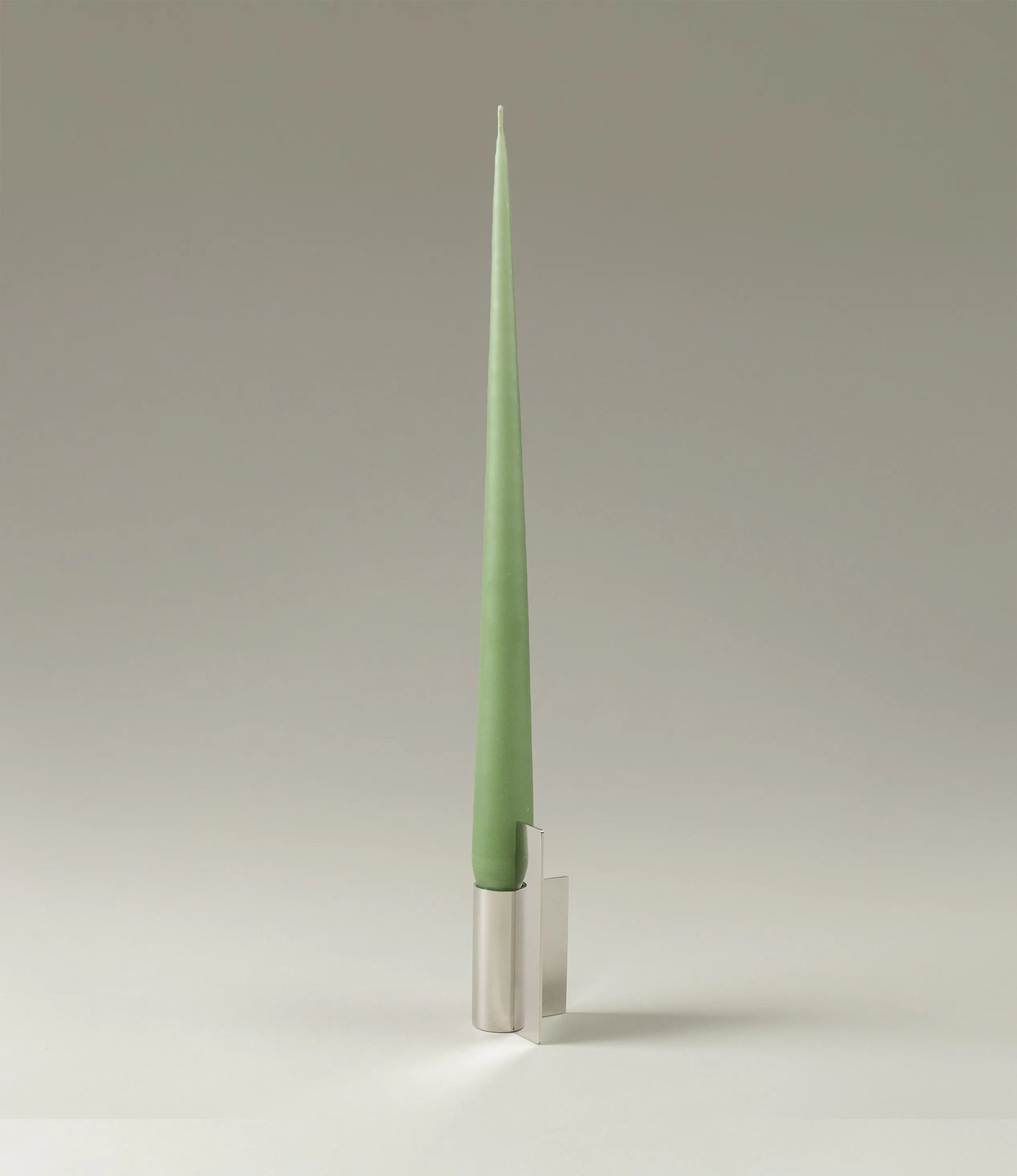 Ester&Erik Taper Candle coming in an eucaliptus shade. The product is showcased in a stainless steel Icon Candleholder from Stences.