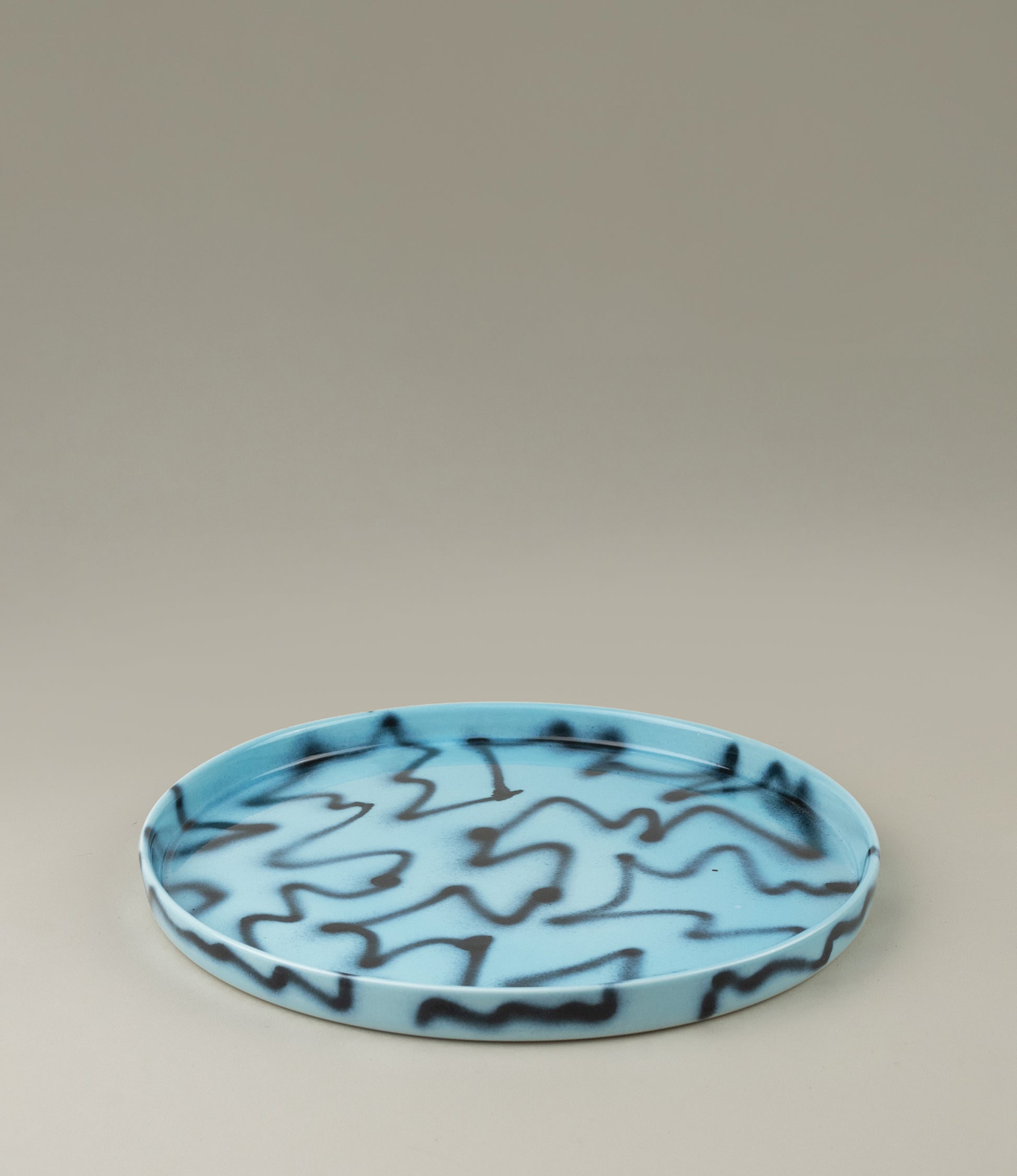 Blue Pizza Tray from Frizbee Ceramics. The tray is coming in the soothing light blue color matched with the contrasting black zig-zag pattern.