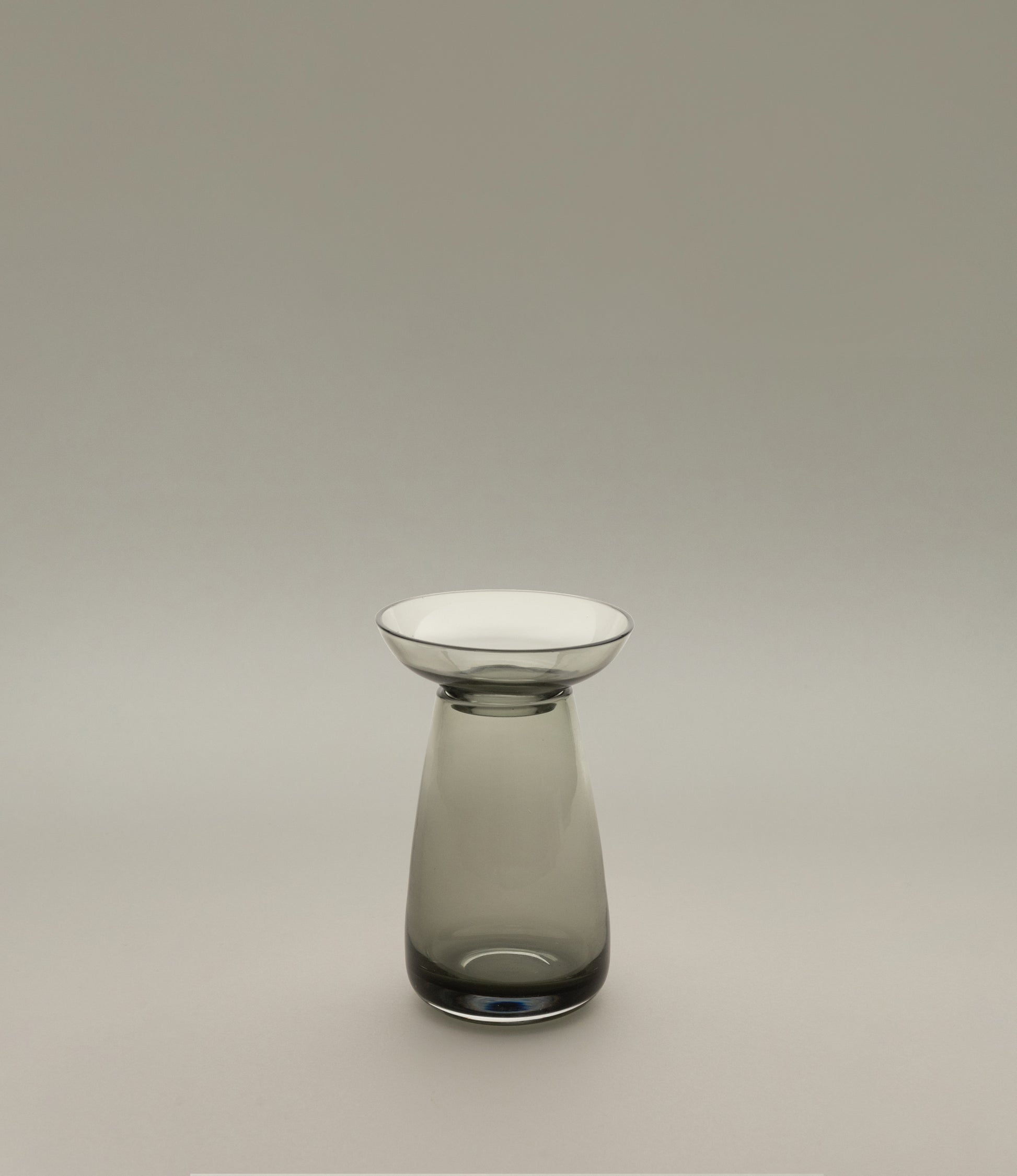 Aqua Culture Vase small from Kinto is a vase to grow new plants. The vase consists of two pieces, a base and a dish for the top, which holds the bulbs, seeds or leaves. This variant is made of a gray glass.