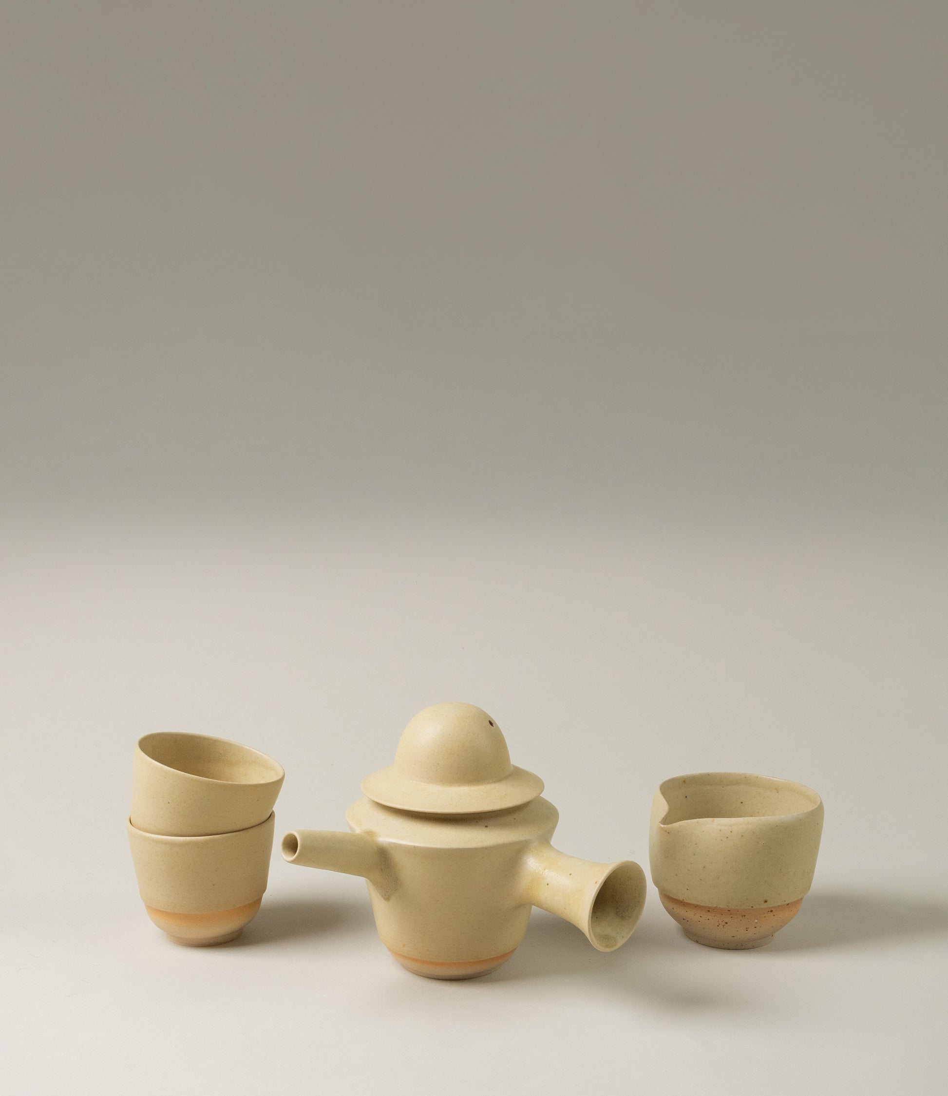 A set from Omni Ceramics for the special tea rituals. The unique shaped teapot, the 2 cups and the pourer are the perfect match. The subtle beige color with the soft radient orange glow on the bottom are a nice touch to any kitchen or dining room.